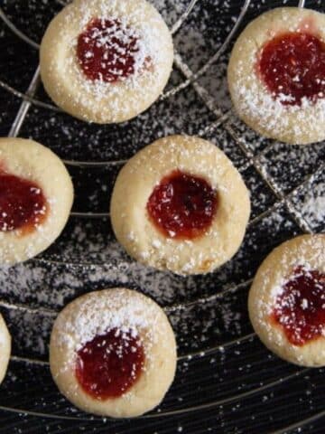 german thumbprint cookies filled with jam on a wire rack.