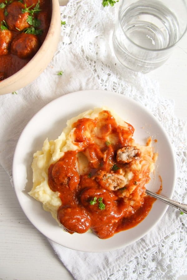 plate of pork meatballs in tomato sauce with mashed potatoes