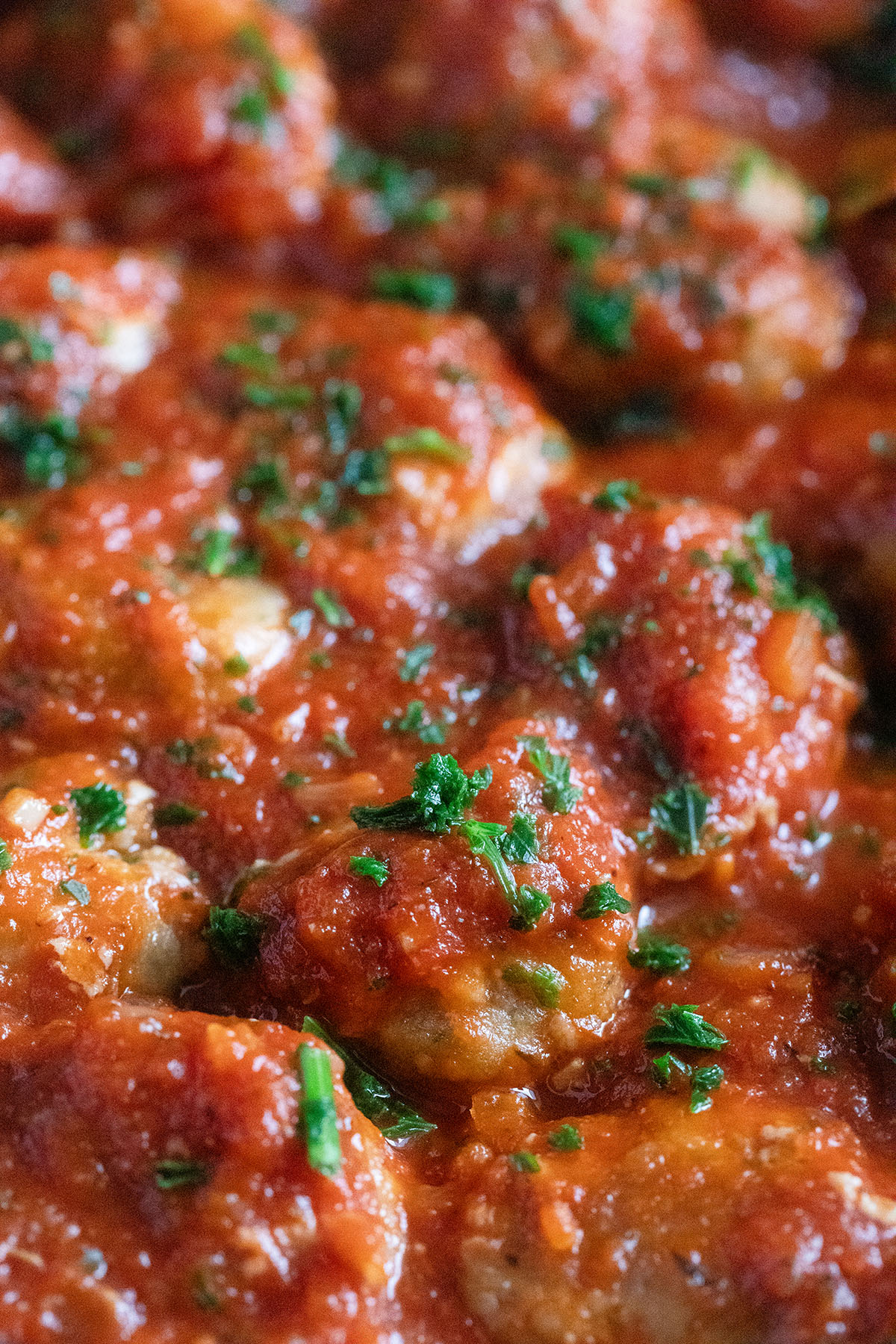 pork meatballs covered in tomato sauce and sprinkled with parsley.