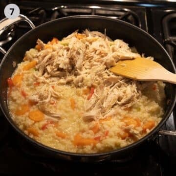 mixing shredded chicken into rice pilaf with a wooden spatula.