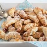 many mini croissants with jam on a serving tray.