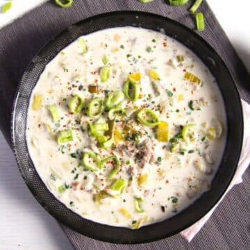 german cheese and leek soup in a black bowl.