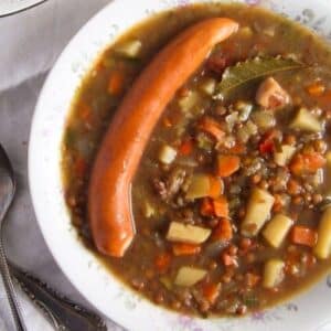 german lentil soup with wiener sausage and potatoes in a vintage soup plate.