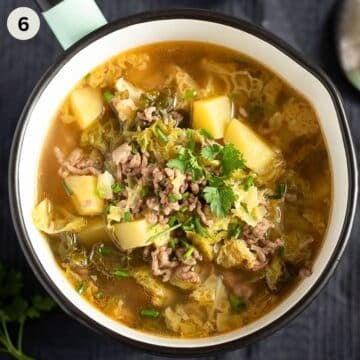 savoy cabbage soup served in a small pot and sprinkled with parsley.