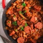 polish sauerkraut stew with sausages and pork in a red cast-iron pot