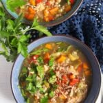 buckwheat chicken soup with vegetables and parsley in a blue bowl