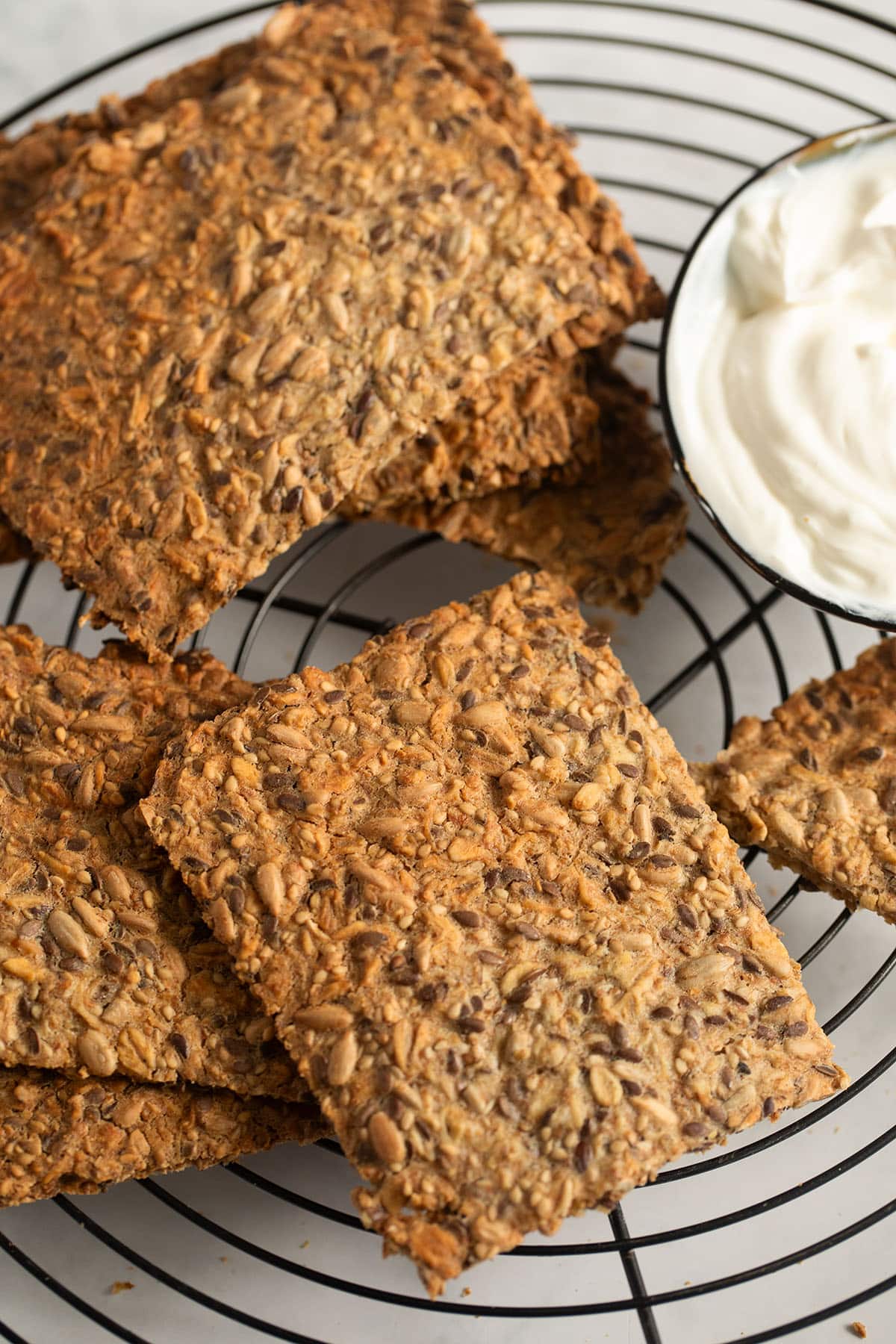 many pieces of golden brown crispbread on a wire rack. 