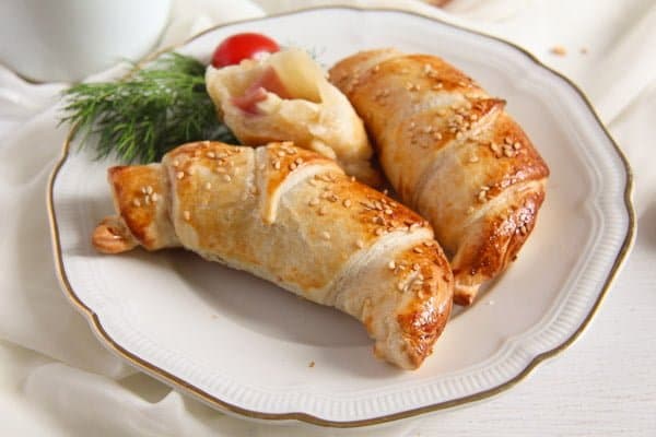ham and cheese puff pastry croissants on a small vintage plate