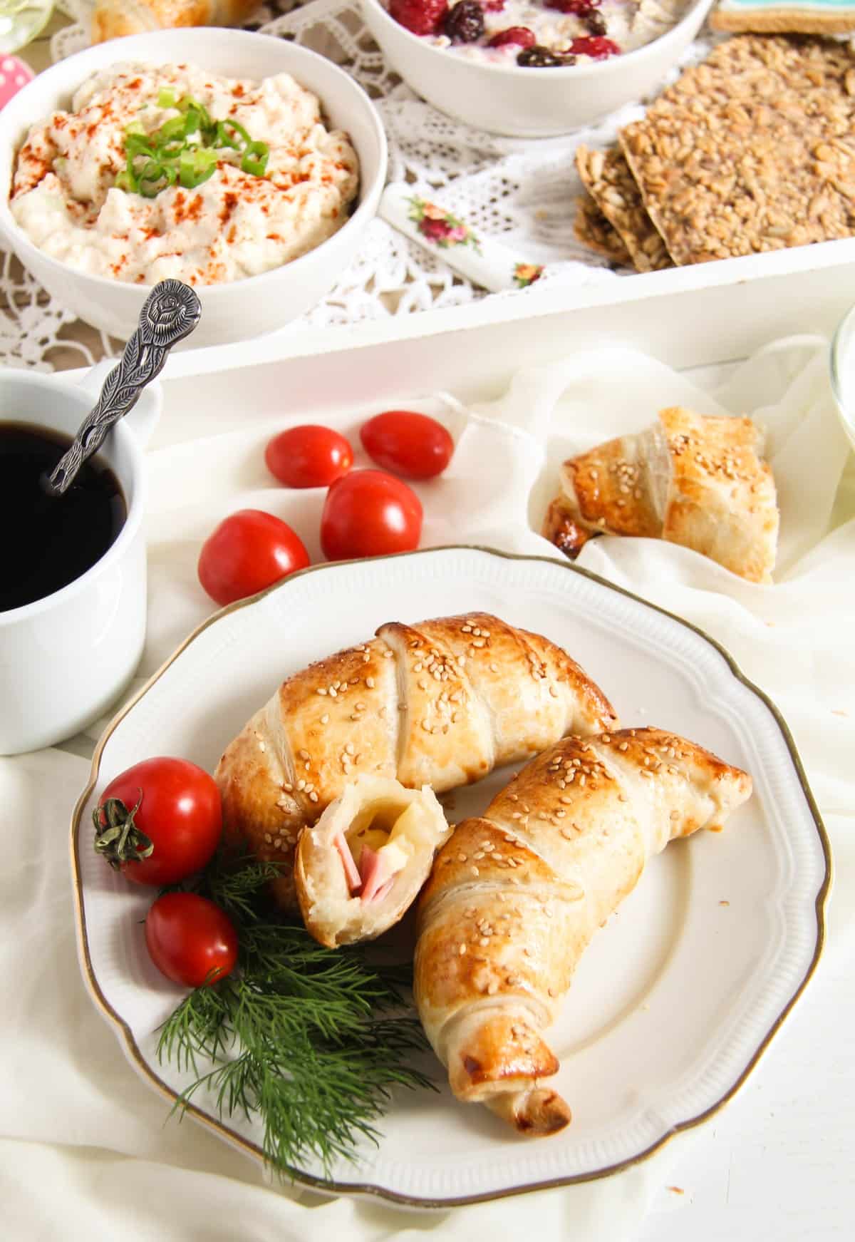 plate with croissants, cherry tomates, coffee and cheese spread for brunch.
