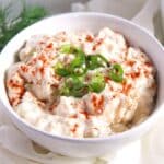 camembert spread sprinkled with paprika and chopped green onions in a small bowl.