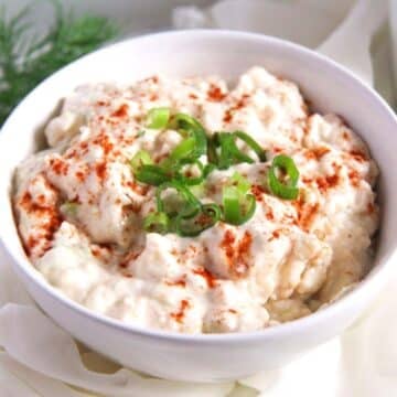 camembert spread sprinkled with paprika and chopped green onions in a small bowl.