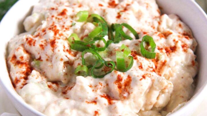 camembert spread sprinkled with paprika and chopped green onions in a small bowl.