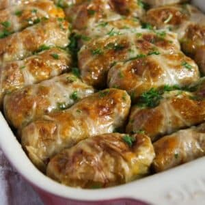 many golden vegan stuffed cabbage rolls in a baking dish.