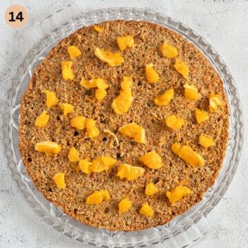 topping a slice of cake with orange pieces before adding the filling.