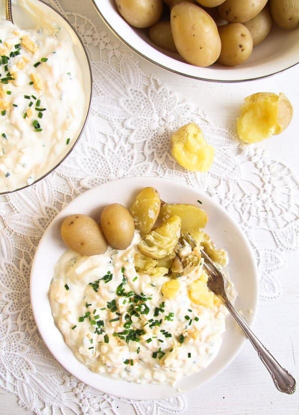 plate with cooked split potatoes and lots of egg sauce with chives