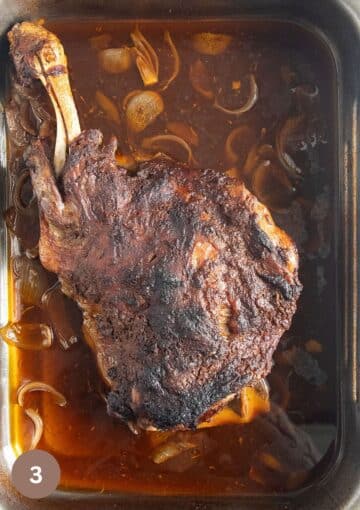 browned leg shoulder with gravy around it in a large roasting tin.