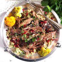 shredded lamb shoulder with pomegranate on a silver plate.