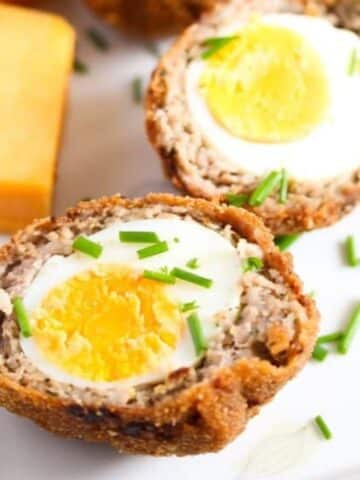 two scotch egg halves showing the egg inside.