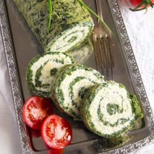 spinach roll with cheese sliced and served with small tomatoes.