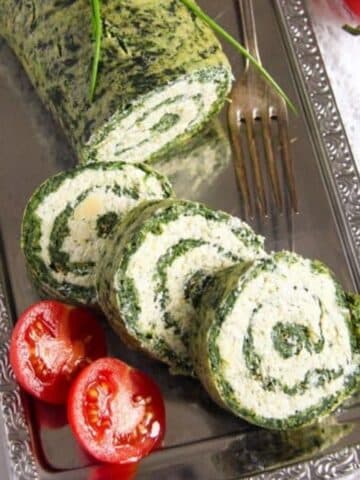 spinach roll with cheese sliced and served with small tomatoes.