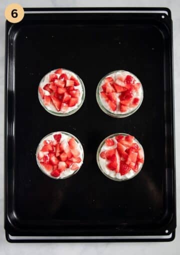 four small cups with layered strawberry and meringue dessert.