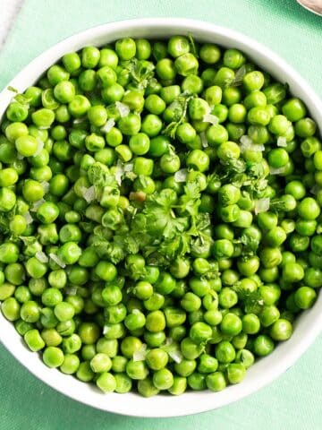 butter peas sprinkled with parsley on a green kitchen cloth.