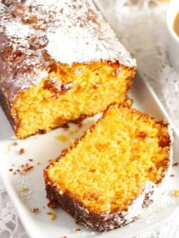 sliced carrot and coconut cake sprinkled with powdered sugar and a cup of tea.