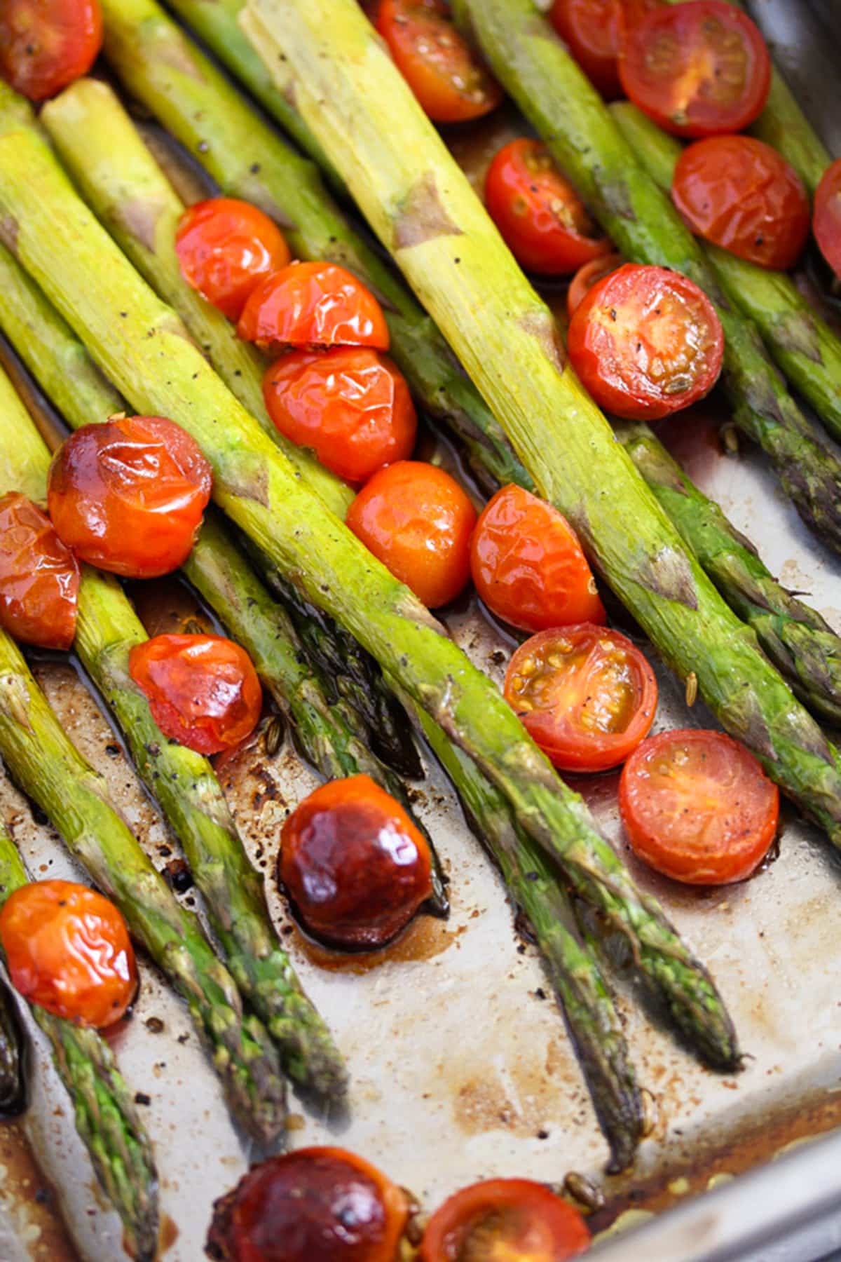 asparagus and cherry tomatoes in a roasting tin.