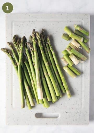 asparagus and their cut woody ends on a cutting board.