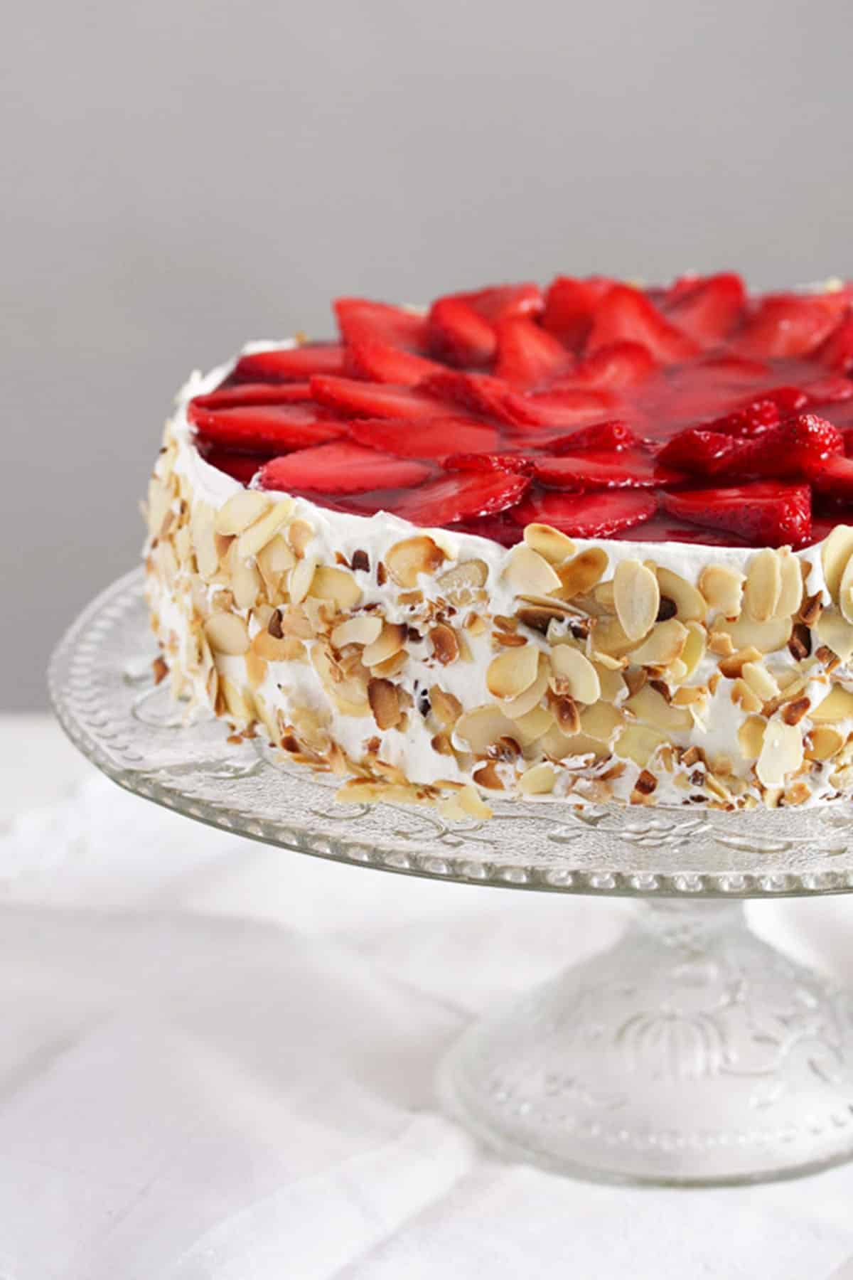 strawberry yogurt cheesecake garnished with almonds on the side on a platter.