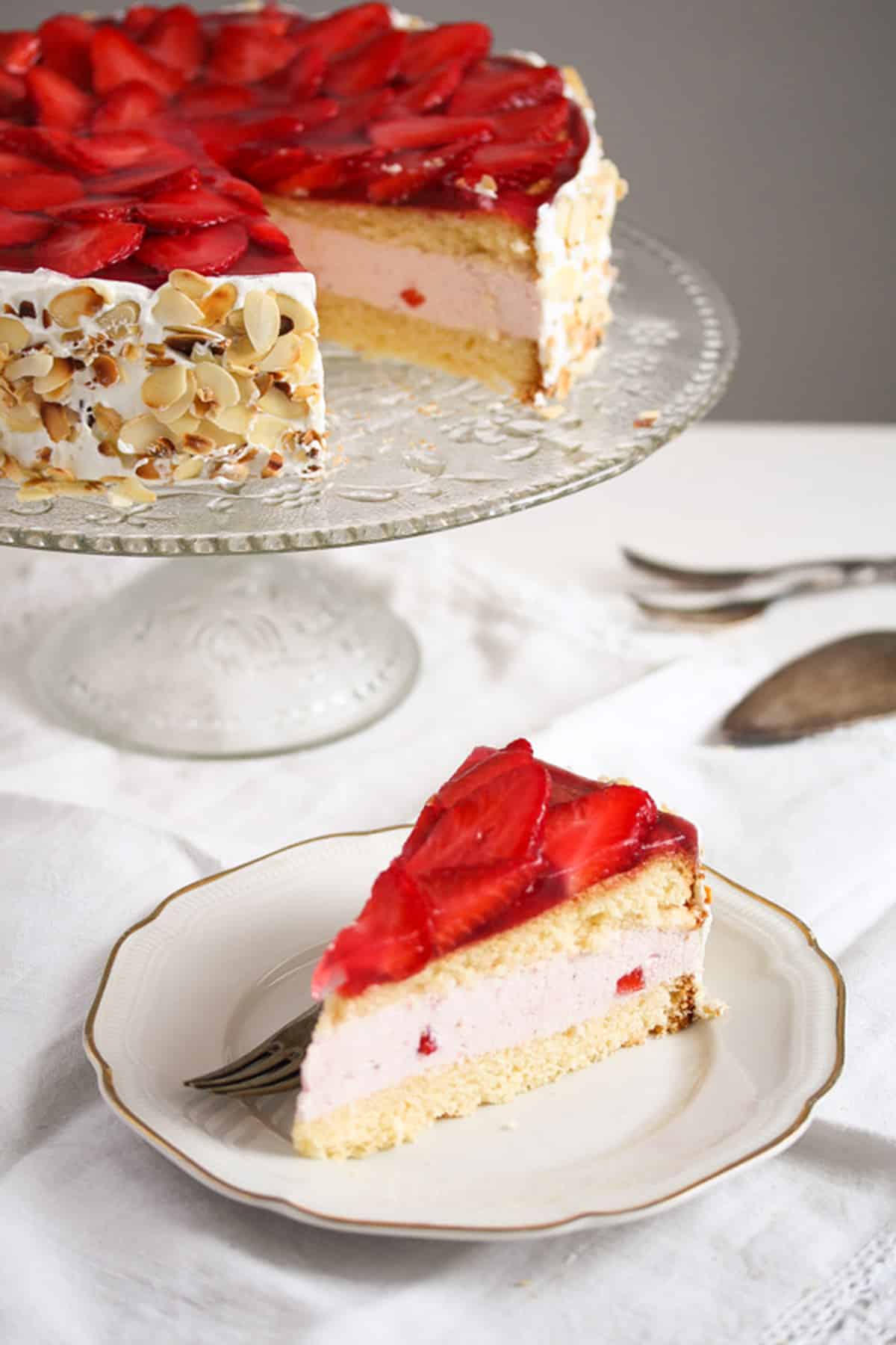 a slice of strawberry cheesecake with yogurt filling on a plate, the rest of it behind it.