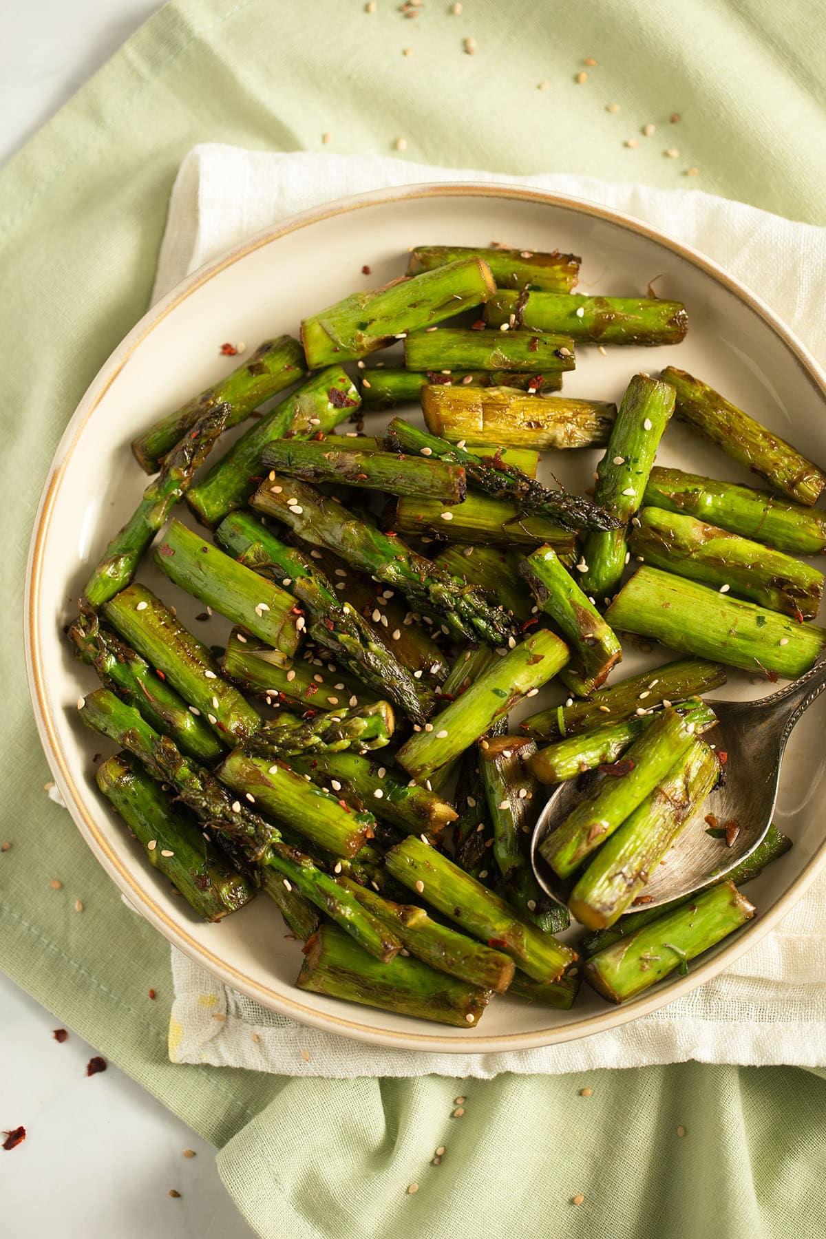 a plate of cooked asparagus sprinkled with sesame seeds.