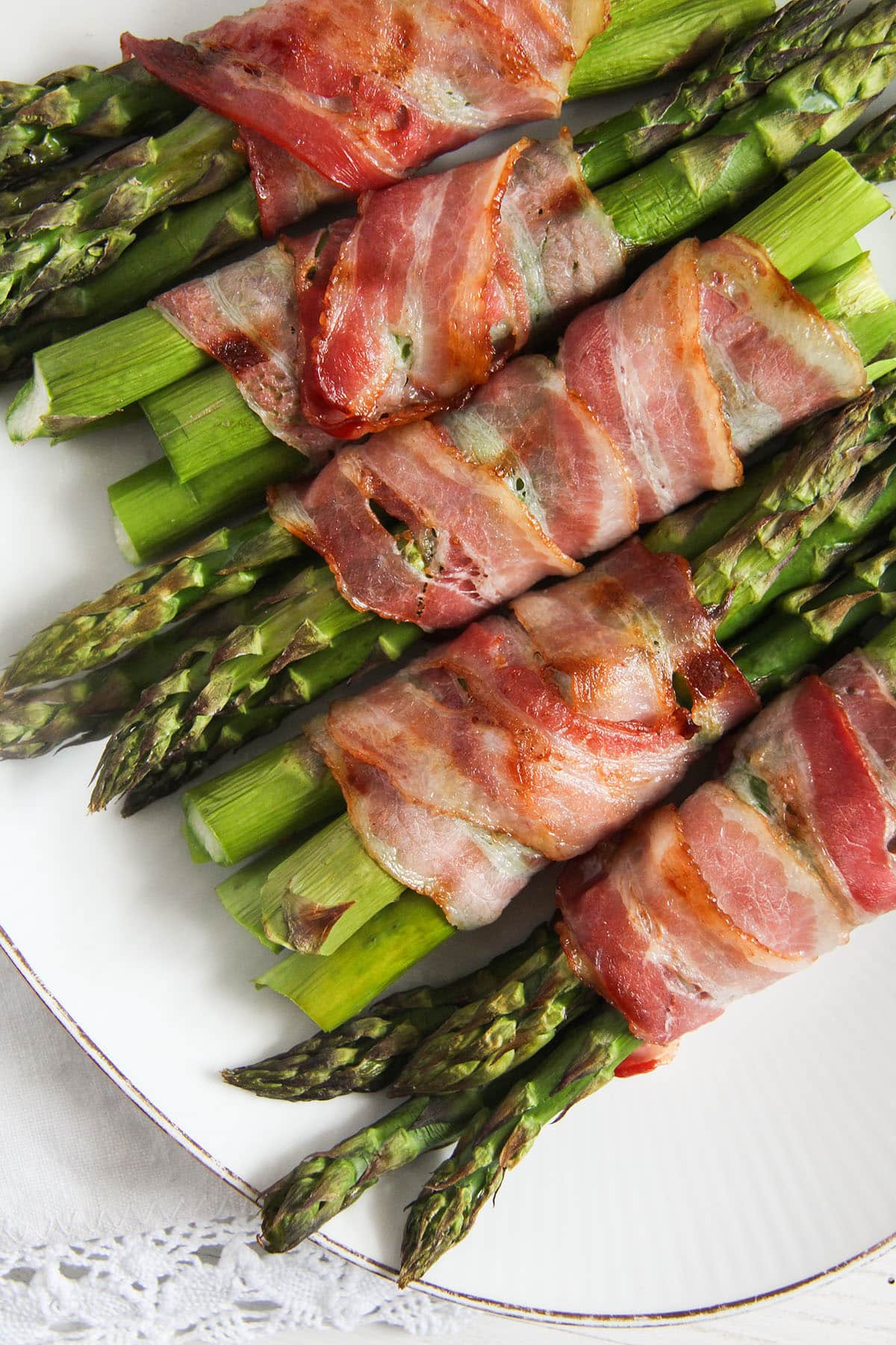 asparagus wrapped in bacon on a serving plate.