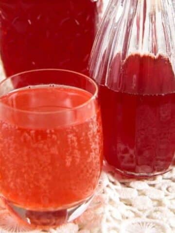 canned strawberry syrup in two small bottle and mixed with water in a small glass.