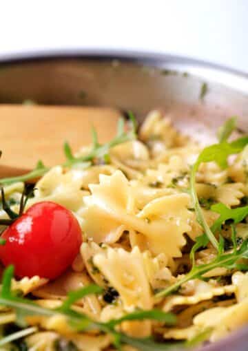 mixing bow tie pasta with tomatoes and herbs.