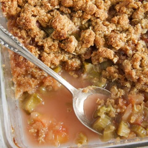 rhubarb crisp with oats and apples being served with a spoon