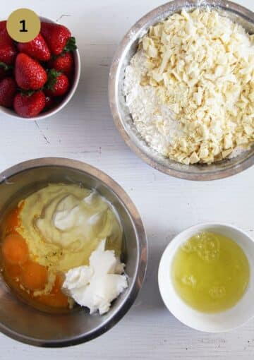 bowls with strawberries, chopped white chocolate, egg whites and ingredients for making muffins.