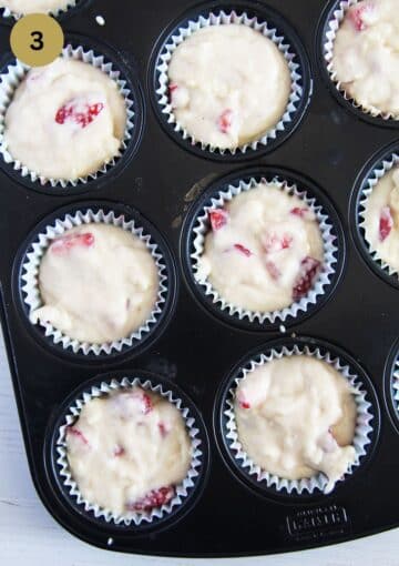 unbaked muffins with strawberry pieces in a muffin tin.