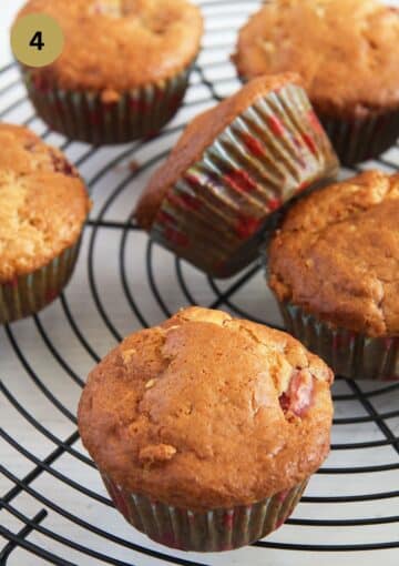 many muffins with strawberries on a wire rack.