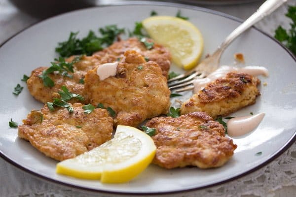 russian chicken fritters served with lemon slices on a white plate