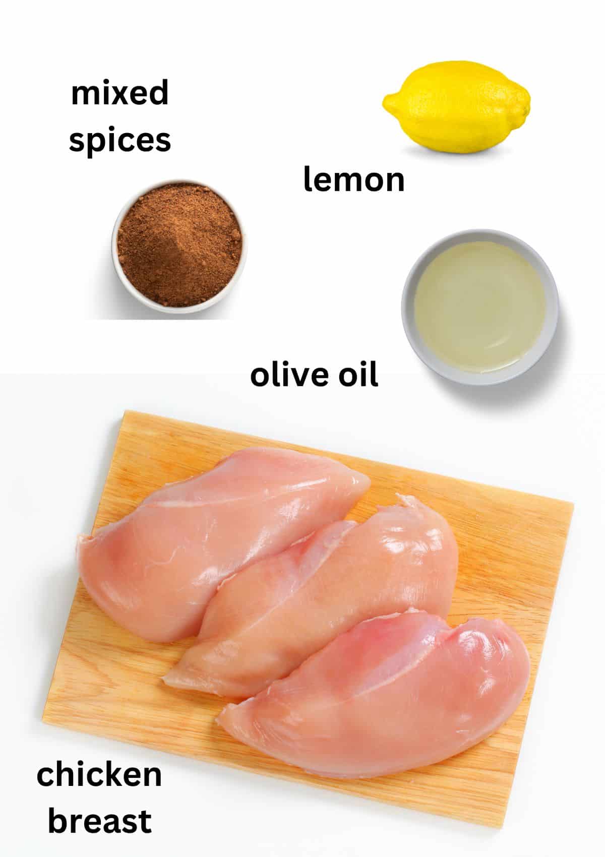 raw chicken breast on a wooden board, olive oil and spices in bowls and a lemon.