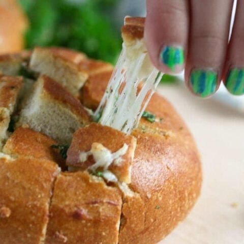girl hand pulling a piece of cheese bread with garlic