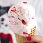 no churn condensed milk strawberry ice cream in a cone held by a girl's hand