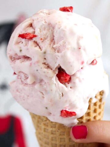 no churn condensed milk strawberry ice cream in a cone held by a girl's hand