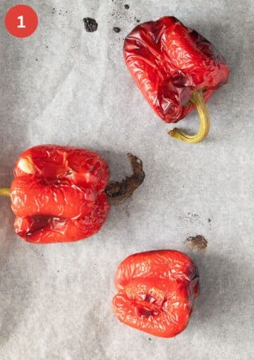 three roasted red bell peppers on white parchment paper.
