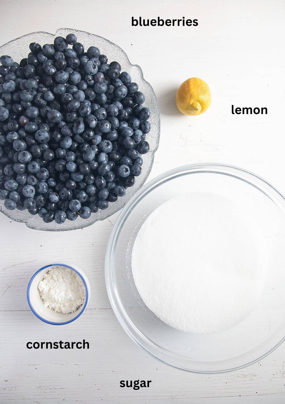 labeled ingredients for making sauce wiht fresh blueberries, granulated sugar, lemon, and cornstarch.