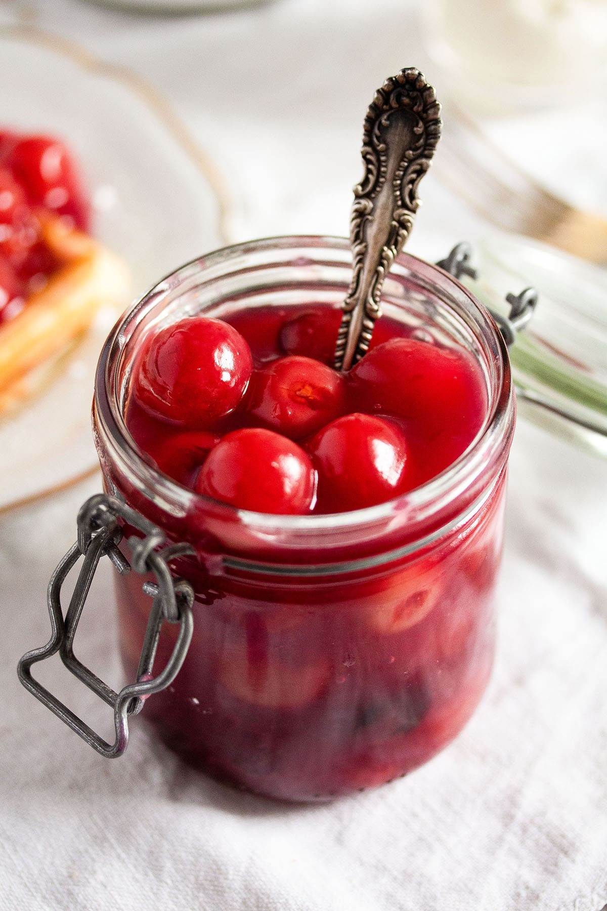 cherry sauce in a jar with a spoon in it.