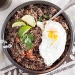 costa rican black beans and rice topped with fried egg and lime wedges.