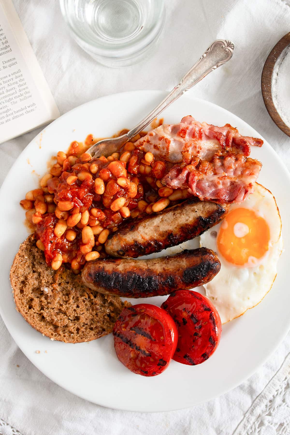 full english breakfast with baked beans, sausages, fried egg, tomatoes and bread.