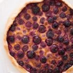 close up of swiss cherry pie with golden crust and many cherries.